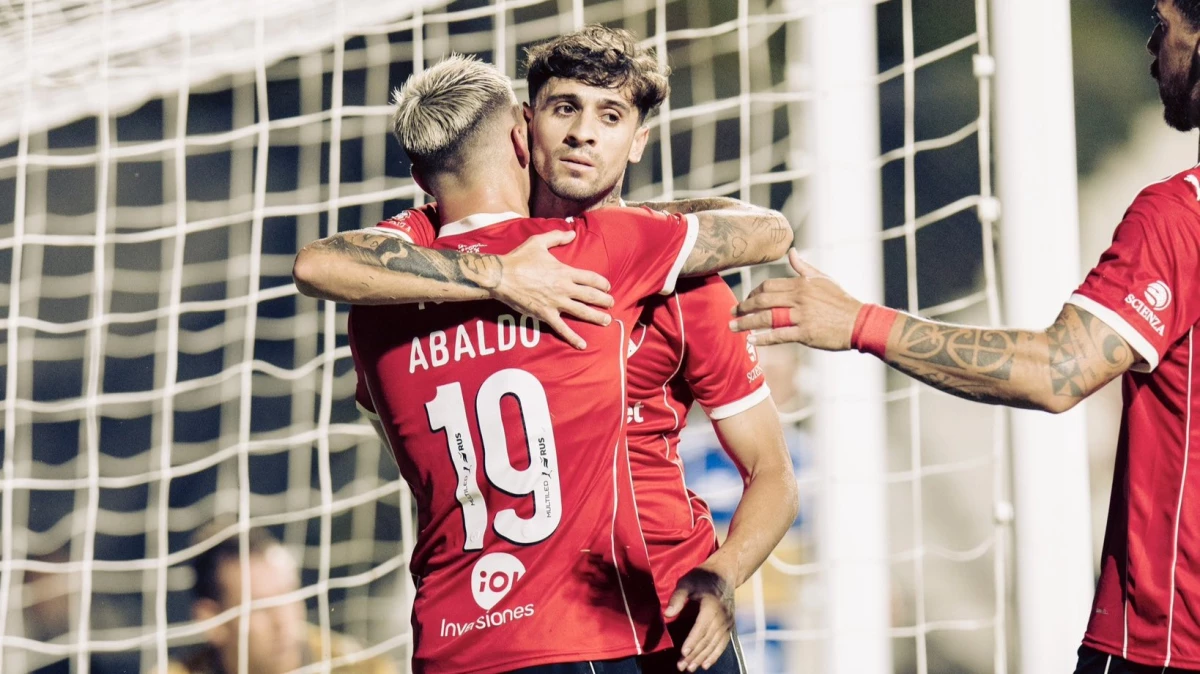 Foto: El uruguayo Matías Abaldo es abrazado por Mazzanti tras recibir la asistencia para el primer gol del “rojo”.